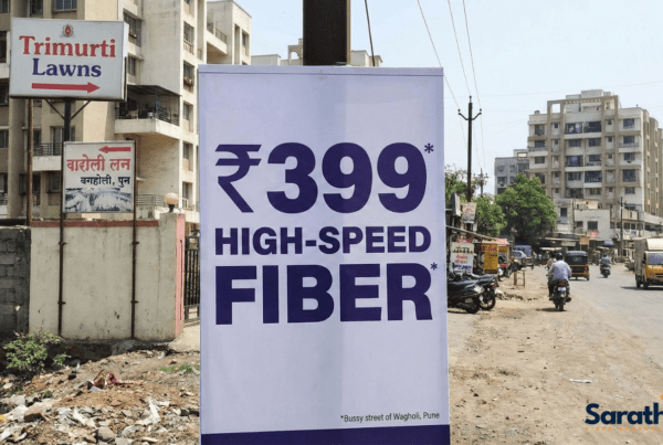 A roadside banner in Wagholi, Pune, advertising "₹399 HIGH-SPEED FIBER" with a small asterisk, located near Trimurti Lawns.