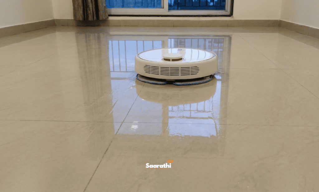A hybrid robot vacuum and mop hybrid unit, mopping a expansive, highly polished beige vitrified tile floor in an apartment on Porwal Road, Wagholi.