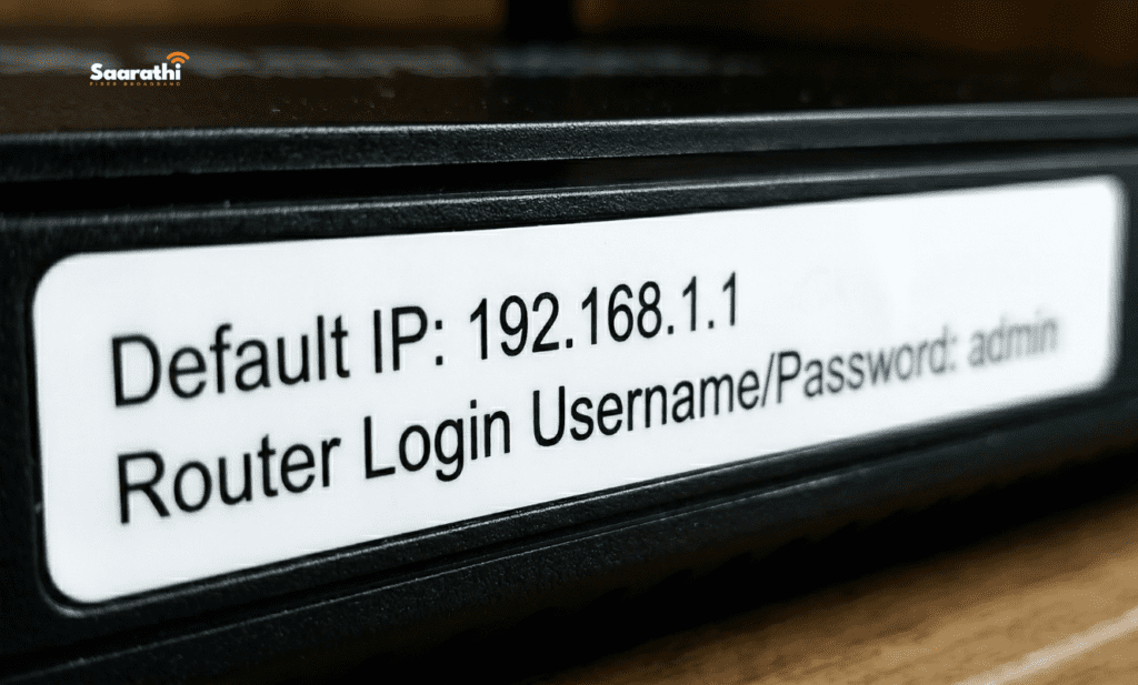 A close-up photography focused on the printed text on the sticker of a modern black Saarathi Fiber Broadband router showing 'Default IP: 192.168.1.1' and 'Router Login Username/Password: admin', essential details required to change WiFi password from mobile.